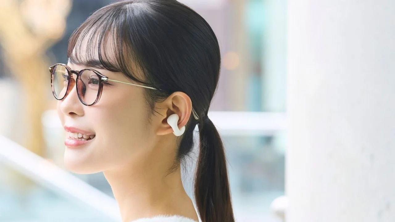 メガネをかけた女性が白いイヤホンを装着し、微笑んでいる画像